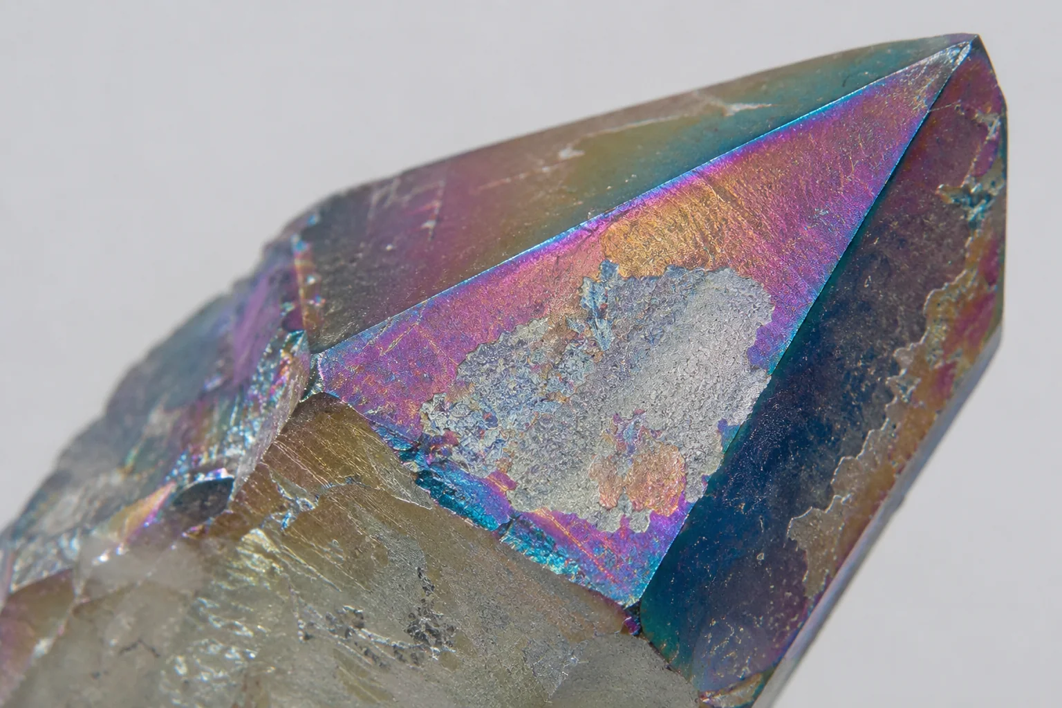 A close-up shot showing the iridescent coating flaking off an aura quartz crystal.