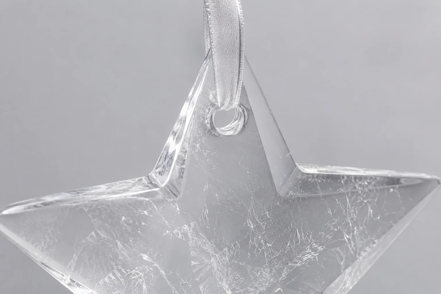 A close-up image showing the drill hole on a clear quartz star ornament, with a ribbon threaded through it.