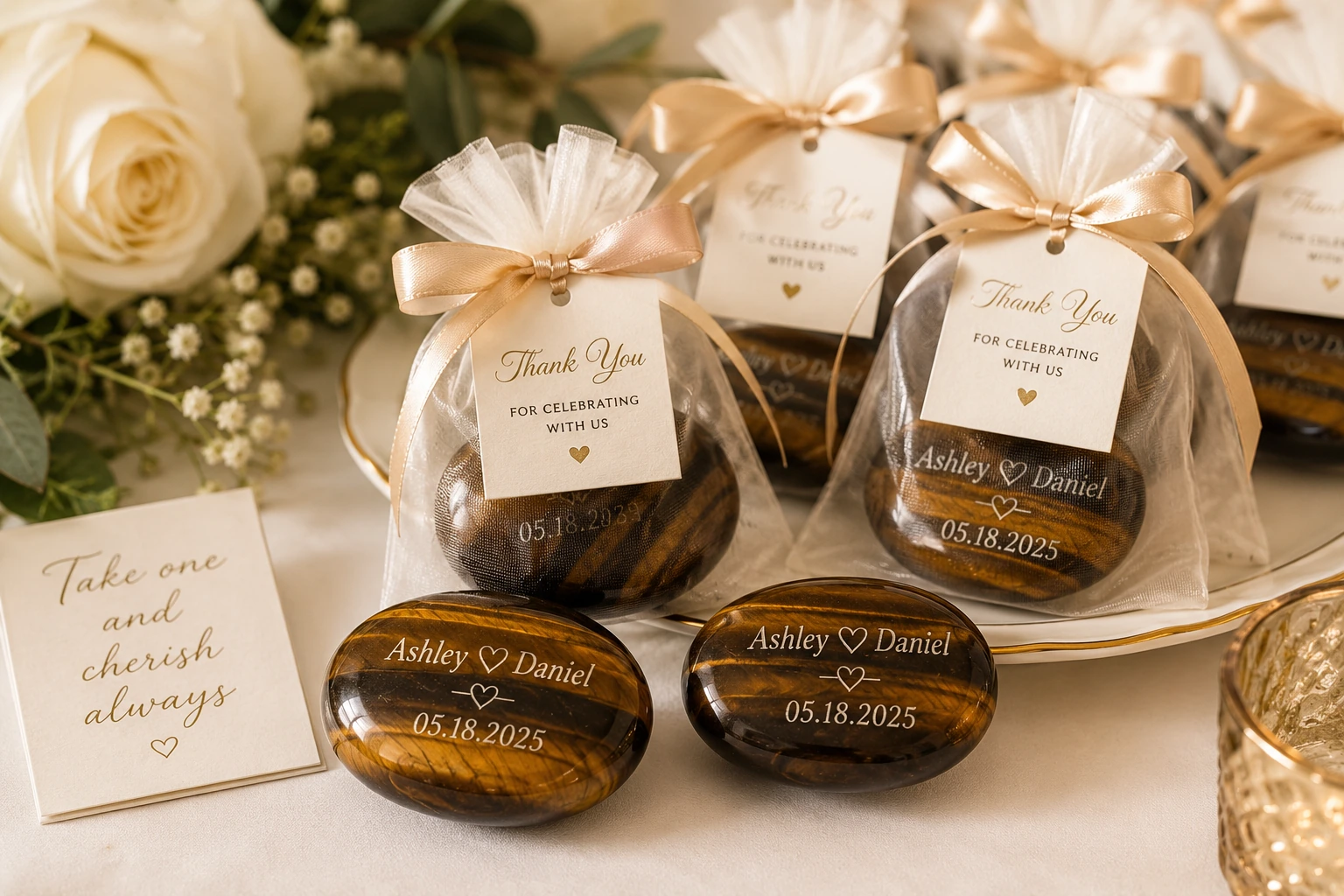 Personalized crystal wedding favors, such as engraved tiger eye palm stones in small gift bags.
