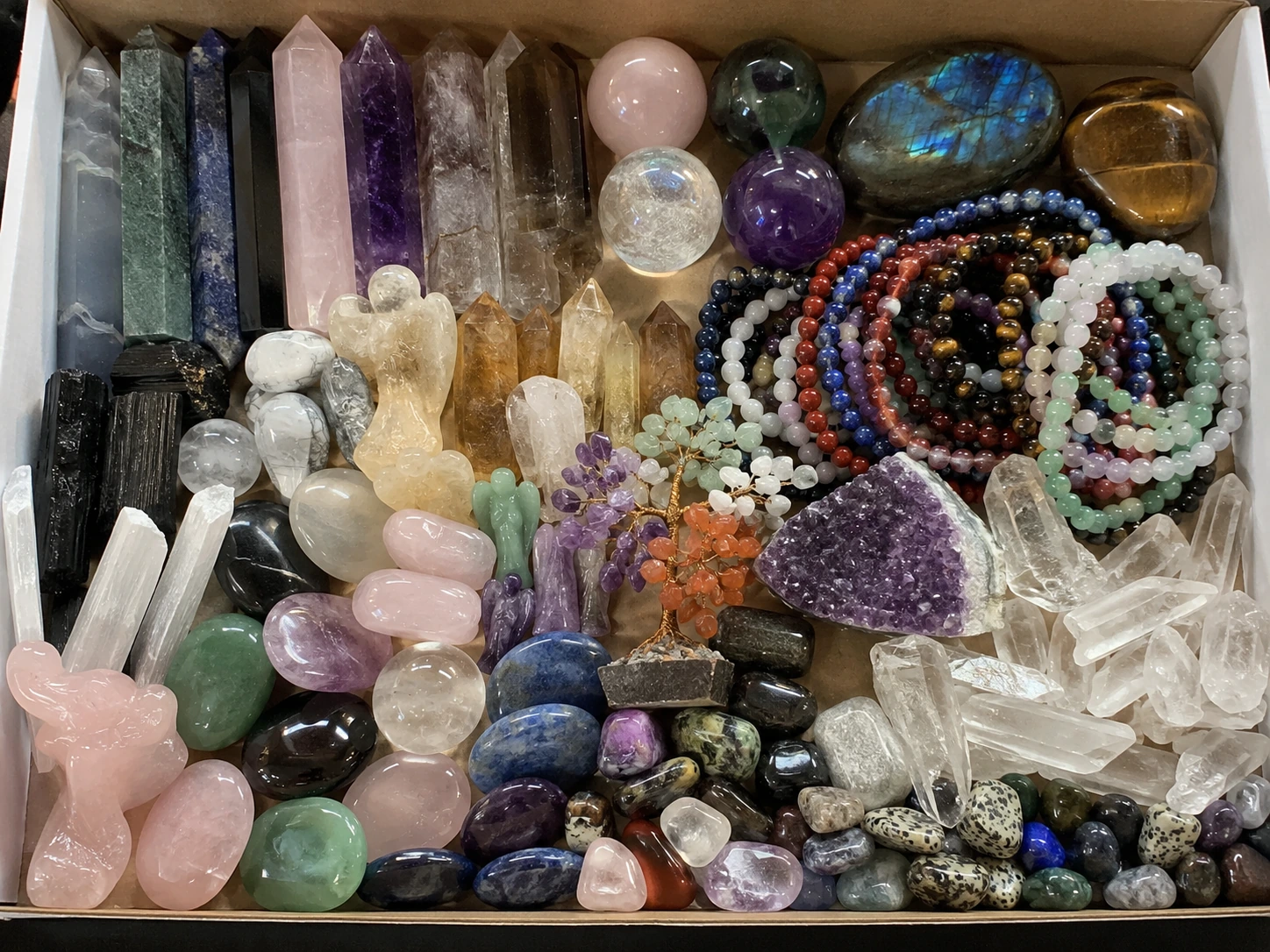 A colorful assortment of different crystal carvings in a single box, representing a low-MOQ mixed lot.