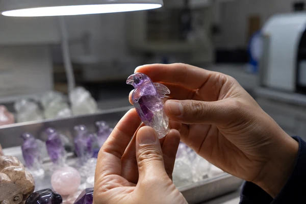 Inspecting a Crystal Carving from a Manufacturer A close-up of a person's hands inspecting a polished crystal carving.