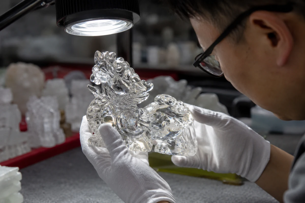 A close-up of a detailed crystal carving being inspected under a bright light, highlighting its intricate details.