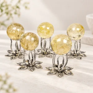 Citrine crystal spheres displayed on decorative silver lotus stands in a light minimalist tabletop setting.