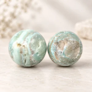 Two pale aqua crystal spheres with natural banding on a soft beige background