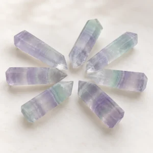 Seven purple and green fluorite crystal towers arranged in a radial fan layout for product display.