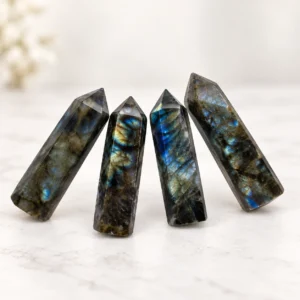 Four rainbow moonstone crystal towers displayed in a clean tabletop scene with soft natural light.