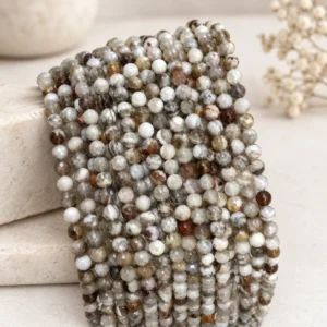 Gray white and brown faceted gemstone bead strands draped on a neutral display form