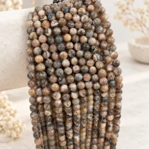 Earth tone natural gemstone round bead strands draped on a neutral display form