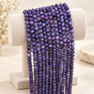 Purple natural gemstone round bead strands draped on a neutral display form