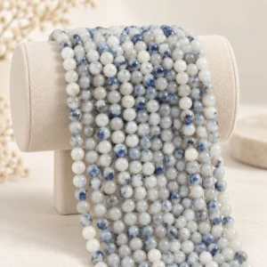 White gray natural gemstone round bead strands draped on a neutral display form