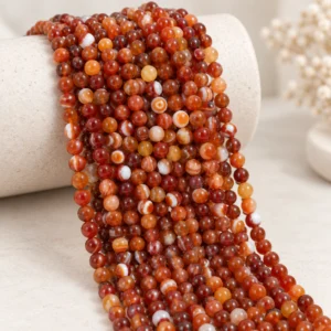 Wholesale Red Banded Agate 6mm round bracelet bead strands displayed on a light minimalist tabletop.