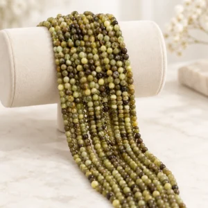 Wholesale Tsavorite Garnet 4mm round bracelet bead strands displayed on a light minimalist tabletop.