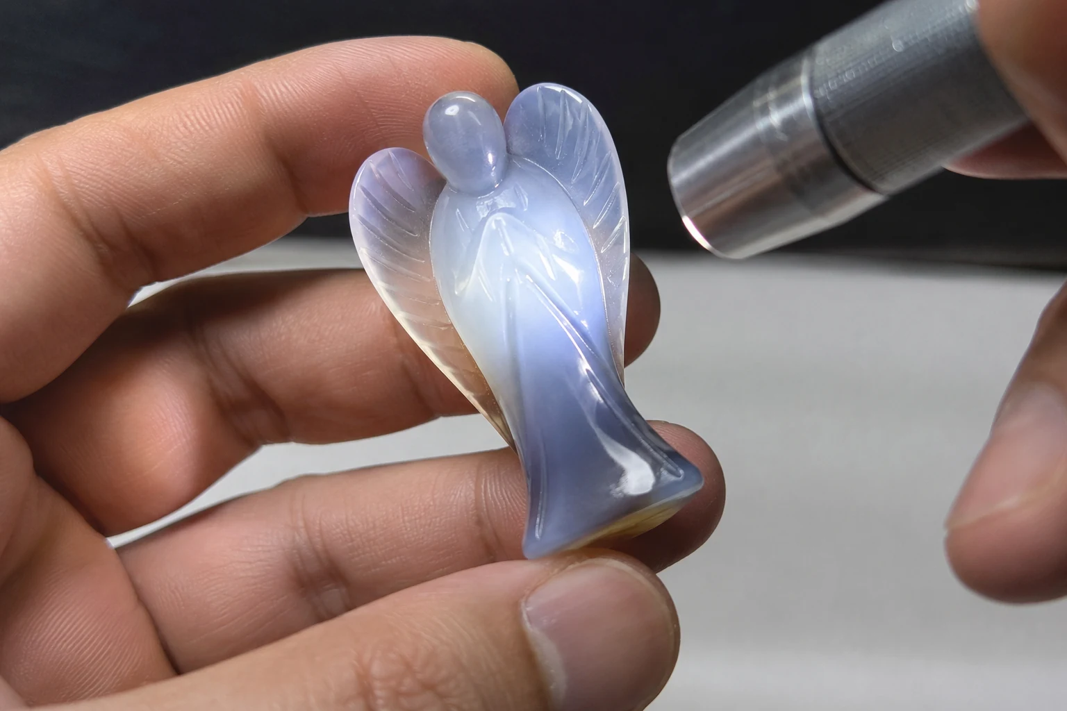 Inspecting Crystal Carving Polish A hand inspecting the polish on a crystal carving under a light