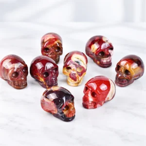 polished agate skull crystal carvings with natural red brown cream and yellow stone patterns on a light tabletop