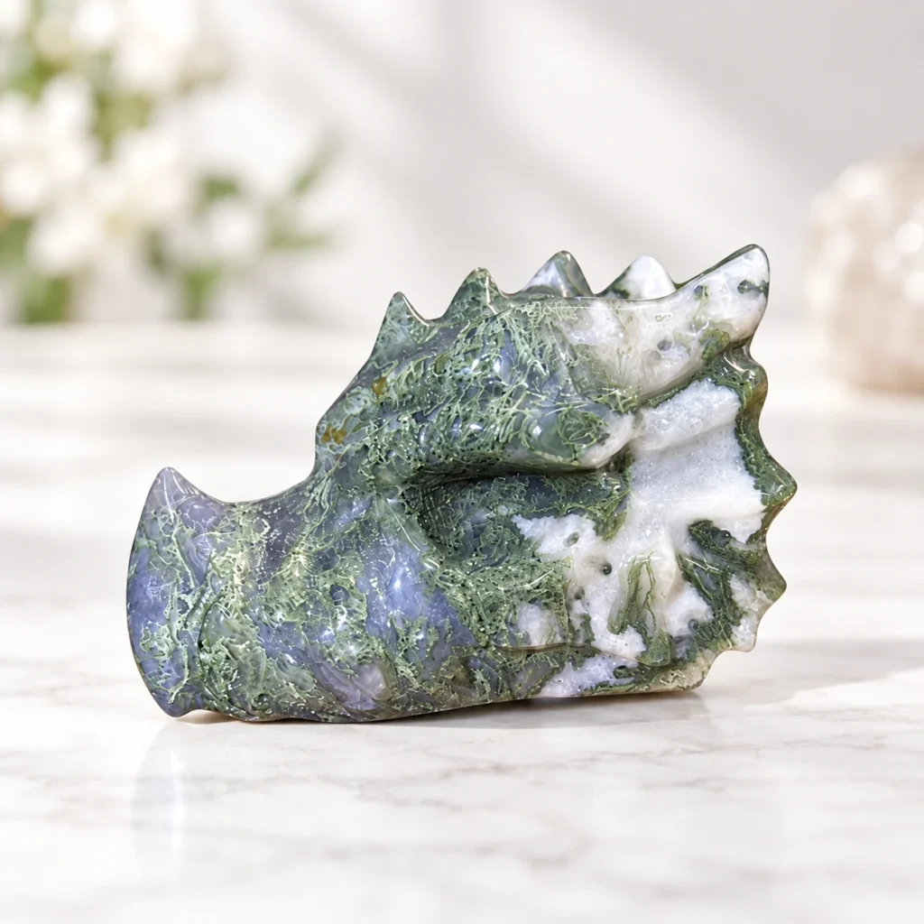 aquatic dragon head crystal carving with natural green white and gray stone patterns on a light minimalist tabletop