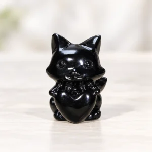 polished black obsidian fox crystal carving centered on a light minimalist tabletop