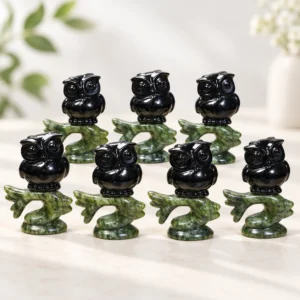 black obsidian owl on branch crystal carvings with green stone bases on a light minimalist tabletop