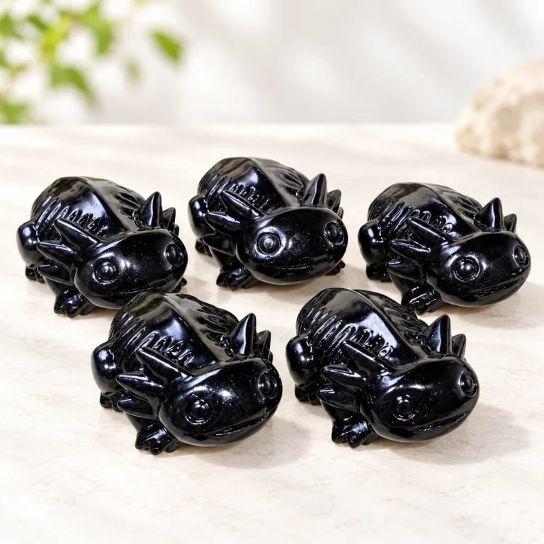 polished black obsidian salamander crystal carvings arranged on a light minimalist tabletop