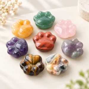 assorted natural crystal cat paw carvings in polished gemstone colors on a light minimalist tabletop