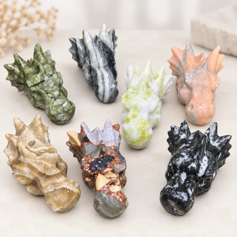 assorted natural crystal dragon head carvings with detailed horns and stone patterns on a light minimalist tabletop