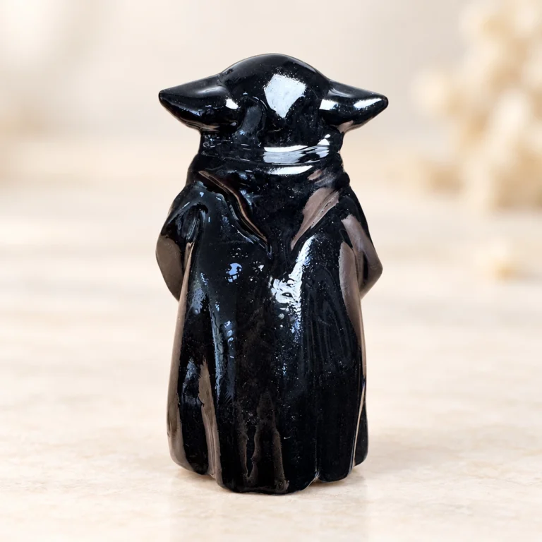Glossy black fantasy wise master crystal carving centered on a light minimalist tabletop