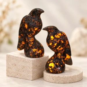 Fire quartz crow crystal carvings with warm orange inclusions displayed on a light minimalist tabletop