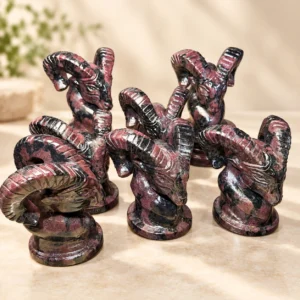 Assorted natural crystal goat head carvings with large curled horns on a light minimalist tabletop