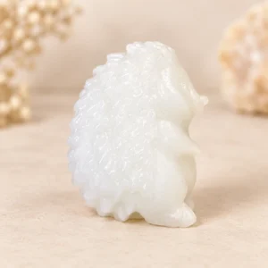 Milky white hedgehog crystal carving with textured spines on a light minimalist tabletop