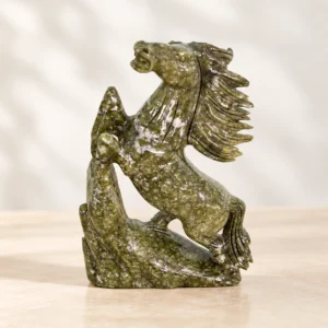 Green natural stone rearing horse crystal carving with flowing mane on a light minimalist tabletop