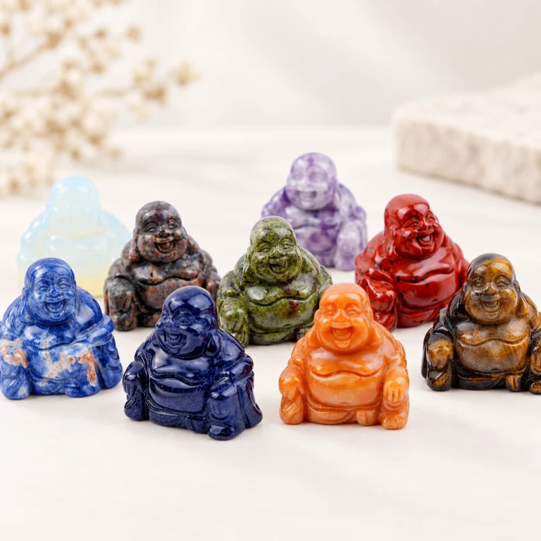 Assorted natural crystal laughing Buddha carvings arranged on a light minimalist tabletop
