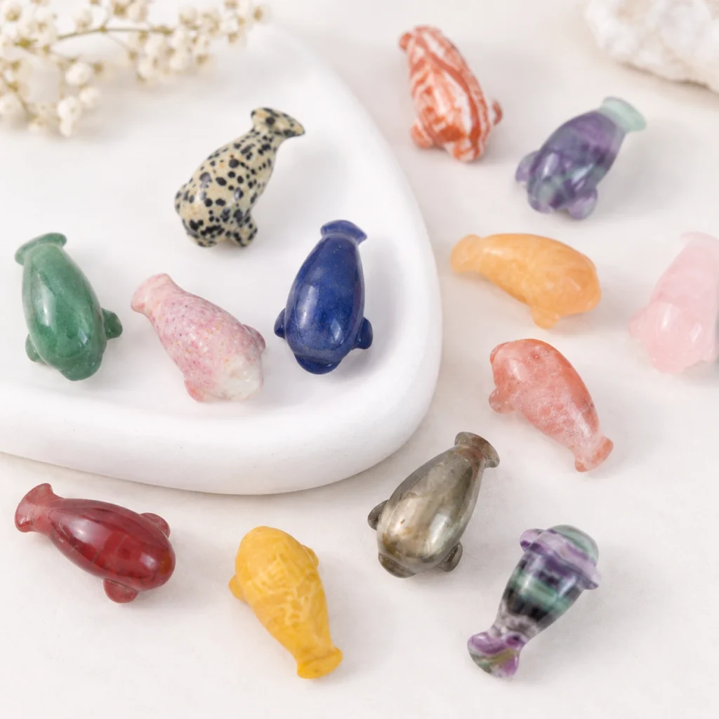Assorted mixed material manatee crystal carvings in multiple natural stone colors on a light minimalist tabletop