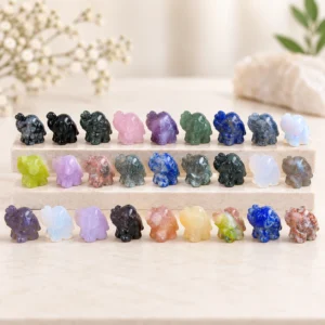 Assorted mixed material mini elephant crystal carvings displayed in rows on a light minimalist tabletop