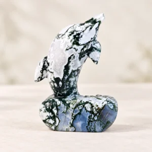 Moss Agate Dolphin Crystal Carving on a light minimalist tabletop background