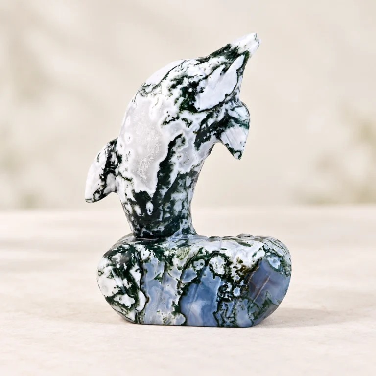Moss Agate Dolphin Crystal Carving on a light minimalist tabletop background