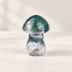 Moss Agate Mushroom Crystal Carving on a light minimalist tabletop background