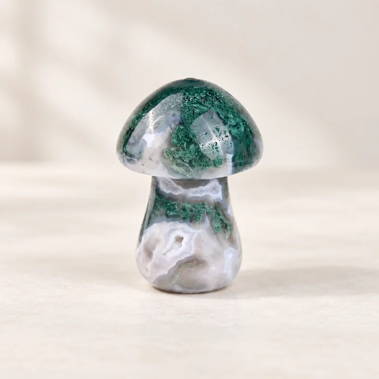 Moss Agate Mushroom Crystal Carving on a light minimalist tabletop background