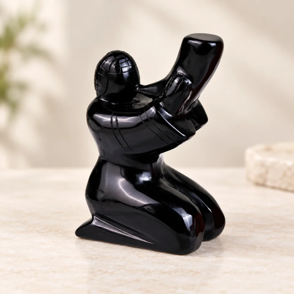 Obsidian Horn Player Crystal Carving on a light minimalist tabletop background