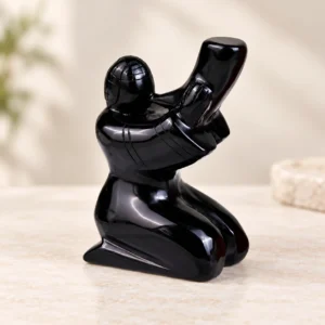 Obsidian Horn Player Crystal Carving on a light minimalist tabletop background