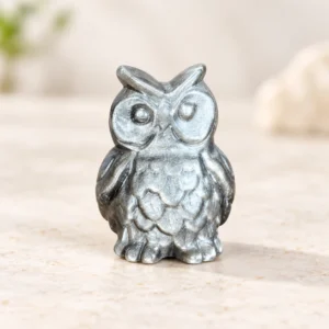 Silver sheen obsidian owl crystal carving with detailed feathers on a light minimalist tabletop