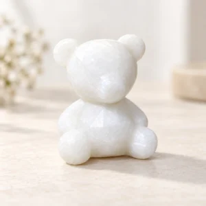 White marble faceless bear crystal carving in a seated pose on a light minimalist tabletop