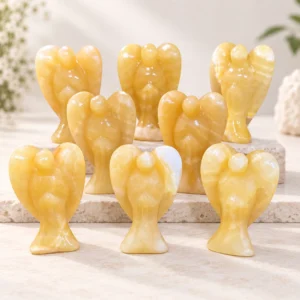 Yellow calcite angel crystal carvings with natural translucent banding on a light minimalist tabletop